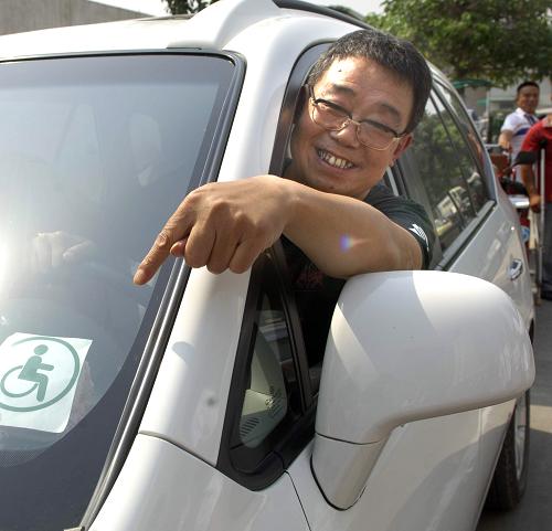 7月6日,領(lǐng)到駕駛證的殘疾人李德有為自己的車貼上了特定的標(biāo)識(shí)。當(dāng)日,西安首批14名殘疾人學(xué)員通過(guò)兩個(gè)多月33個(gè)課時(shí)的學(xué)習(xí),順利通過(guò)了所有交通科目的考試,領(lǐng)取到了專為右下肢殘疾、雙下肢殘疾以及聽(tīng)力障礙、右手拇指缺失或手指末節(jié)殘缺五類殘疾人員設(shè)立的C5駕照,圓了他們的駕車夢(mèng)。新華社發(fā)(劉瀟 攝)