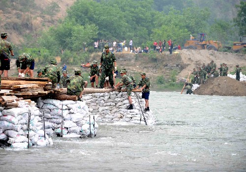 5月17日,解放軍戰(zhàn)士正在涪江上架橋。 在四川地震災(zāi)害中,平武縣南壩鎮(zhèn)交通要道被山體滑坡的砂石完全堵塞,與外界來往僅靠一艘渡船。解放軍空軍某部于16日出動(dòng)官兵800人日夜施工,在涪江上架橋,以盡快打通南壩鎮(zhèn)的運(yùn)輸補(bǔ)給線。 新華社記者 任軍川攝