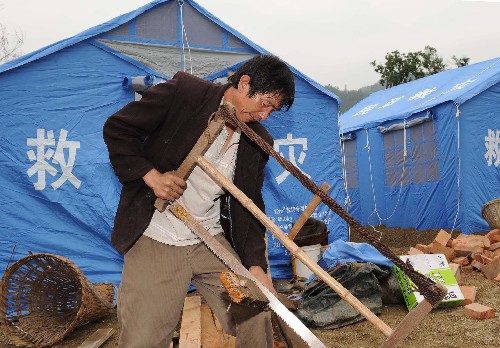 5月21日,在四川省北部的青川縣木魚鎮(zhèn),一名當(dāng)?shù)厝罕娬阡從玖蠝?zhǔn)備搭建帳篷。連日來,四川汶川地震的重災(zāi)區(qū)青川縣的各族群眾積極應(yīng)對災(zāi)情,化悲痛為力量,在黨和政府的關(guān)心及社會各界的幫助下努力開展自救工作。 新華社記者 藺以光 攝