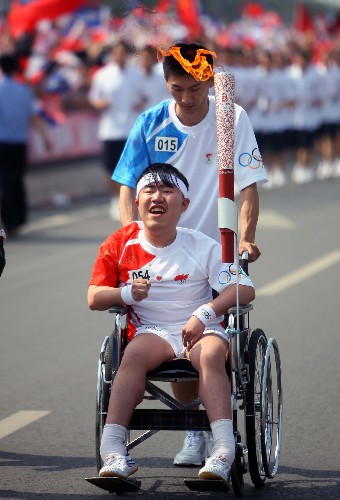 6月26日,奧運火炬手嚴(yán)江坐在輪椅上參加傳遞。當(dāng)日,北京奧運圣火在山西太原傳遞。 新華社記者邢廣利攝