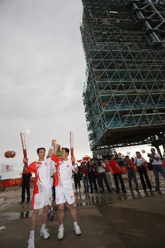 6月28日,火炬手費(fèi)俊龍(左)與火炬手郭保新在發(fā)射塔架下交接。當(dāng)日,北京奧運(yùn)圣火在東風(fēng)航天城傳遞。 新華社記者 李剛 攝