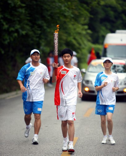 5月15日,奧運(yùn)火炬手孟嘉麒手持火炬?zhèn)鬟f。新華社記者 邢廣利 攝