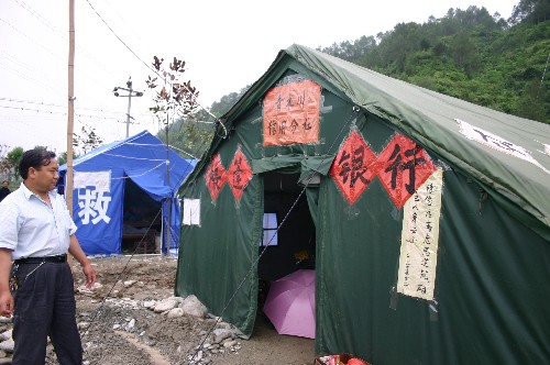 這是陜西省寧強(qiáng)縣青木川鎮(zhèn)一處安置點(diǎn)開設(shè)的帳篷銀行(5月29日攝)。青木川是陜西省距離四川震區(qū)最近的鄉(xiāng)鎮(zhèn),離四川青川咫尺。“5·12”地震,使這里成了廢墟。街道中間破碎的瓦礫,隱約顯現(xiàn)當(dāng)時(shí)的恐怖。雖然零星余震不斷,但近日記者在青木川鎮(zhèn)街道看到了熱鬧的集市,新鮮蔬菜和日常用品在這里都可以買到。新華社記者 段博 攝