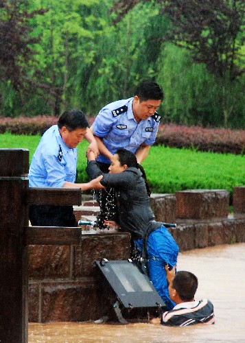 6月10日,休寧縣吳田村一名女子路過被洪水圍困的萬安學府廣場時,不慎落入廣場東側(cè)的水溝內(nèi),守在此處的民警和民兵應(yīng)急小分隊成員聽到求救聲后迅速跳入水中,將落水女子成功救起。 新華社發(fā)(黃俊軍 攝)