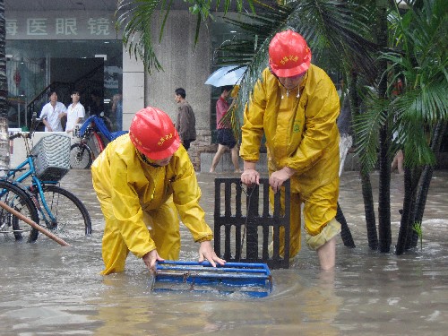 10月14日,兩名市政工人在海口市龍豐路口疏通下水管道并設(shè)置標(biāo)識,以防行人不慎跌入。新華社記者 鄭瑋娜 攝