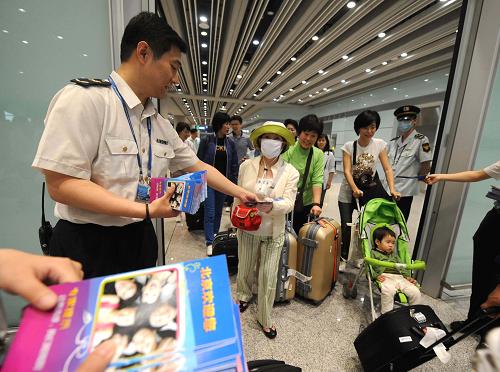 5月15日,首都機(jī)場(chǎng)的工作人員向旅客發(fā)放甲型H1N1防控知識(shí)折頁。新華社記者 李文 攝