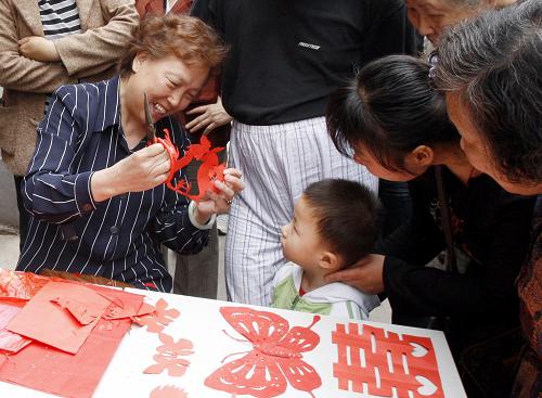 上海盧灣區(qū)里弄一位阿婆在為孩子剪紙(5月17日攝)。新華社記者 張明 攝