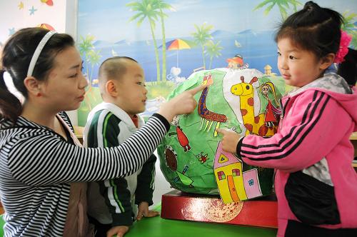 4月21日,河南省淅川縣幼兒園的小朋友利用廢舊紙張制作了一個(gè)地球模型,幼兒園老師(左一)利用模型為孩子們講解保護(hù)水源和動(dòng)植物等知識(shí),迎接世界地球日。新華社發(fā)(周彥波 攝)