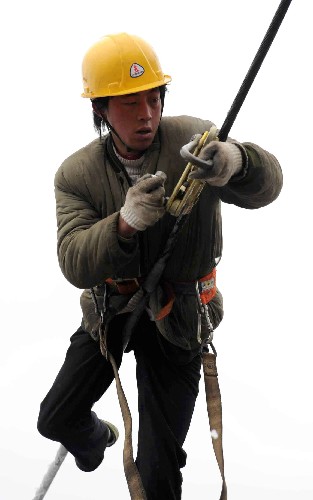 2月2日,在貴陽市圖云關(guān)的一條因雪凝災(zāi)害造成的110千伏輸電線路的損毀現(xiàn)場(chǎng),南方電網(wǎng)公司貴州送變電的一位搶險(xiǎn)人員正在高空架最后一相電。 新華社記者 楊楹 攝