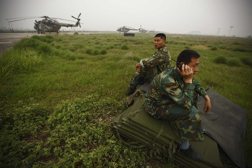 5月25日,在四川綿陽(yáng)機(jī)場(chǎng),兩名武警水電官兵正在詢問(wèn)天氣信息,各類(lèi)直升機(jī)停留在地面待命。 當(dāng)日,唐家山堰塞湖上空云霧籠罩,能見(jiàn)度極差,偵察機(jī)飛至安縣附近就已無(wú)法看清前方情況,無(wú)法運(yùn)入大型挖掘設(shè)施。米-17直升機(jī)返回綿陽(yáng)機(jī)場(chǎng)。 新華社記者才揚(yáng)攝