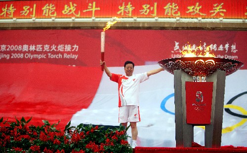 6月28日,火炬手劉克仁點(diǎn)燃圣火盆后高舉火炬。 新華社記者 邢廣利 攝