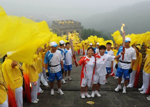 8月7日,火炬手任金鳳(左)與下一棒火炬手祁艷霞交接火炬后慶祝。當(dāng)日,北京奧運(yùn)圣火在北京市傳遞。 新華社記者劉力航攝