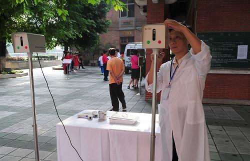6月7日,廣州市第七中學(xué)考場(chǎng)的工作人員在調(diào)試測(cè)溫儀。 當(dāng)日,2009年全國(guó)普通高校招生全國(guó)統(tǒng)一考試開始進(jìn)行。為嚴(yán)防甲型H1N1流感,廣州市要求每個(gè)考場(chǎng)都配備有紅外測(cè)溫儀器。實(shí)施感覺異常考生自行申報(bào)結(jié)合監(jiān)考老師發(fā)現(xiàn)異常抽查測(cè)溫的方法防控甲型H1N1流感。 新華社記者 盧漢欣 攝