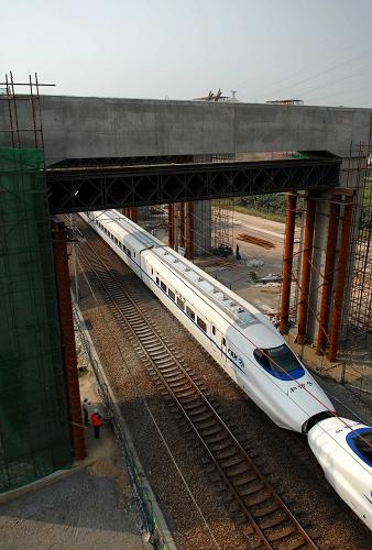 9月11日,列車從滬寧城際鐵路丹陽(yáng)段跨京滬鐵路的門式橋墩下駛過(guò)。 滬寧城際鐵路是長(zhǎng)三角地區(qū)城際軌道交通網(wǎng)規(guī)劃中的網(wǎng)絡(luò)主軸之一,線路全長(zhǎng)297公里,總投資約422億元,計(jì)劃于2010年7月建成通車。屆時(shí)列車時(shí)速可達(dá)300公里以上,從上海至南京只需75分鐘,旅客列車班次最小間隔時(shí)間只有3分鐘,沿線的上海、蘇州、南京等城市之間將實(shí)現(xiàn)鐵路列車公交化。 新華社發(fā)(劉兵生 攝)