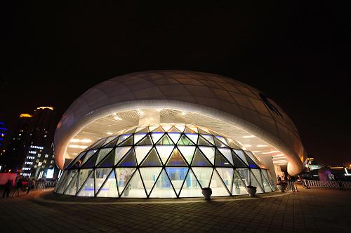 中國航空館夜景。建筑外形設(shè)計(jì)源于一朵變幻的“云朵”,是白云形狀的仿生態(tài)建筑(5月4日攝)。 “我最喜歡飛機(jī),所以今天來排的第一個(gè)隊(duì)就在航空館”,終于進(jìn)入上海世博園中國航空館的香港男孩鄒欣樺十分興奮。 十歲的鄒欣樺和父母一起5月3日才到達(dá)上海,由于學(xué)校課程安排,4日晚就要返回香港,真正在世博園參觀的時(shí)間只有一個(gè)白天,滿打滿算也只能參觀有限的幾個(gè)展館。4日一早,一家三口就早早來到位于世博浦西園區(qū)的中國航空館排隊(duì),趕在第一批順利進(jìn)入航空館。 以《飛翔之夢》為主題的主展區(qū),緊密圍繞航空、城市、未來展開,館內(nèi)有很多表現(xiàn)航空未來的元素:從前展區(qū)的未來飛行器概念模型,到后展區(qū)的LED光學(xué)無線網(wǎng)絡(luò)、未來城市飛行交通網(wǎng)模擬沙盤,以及主展區(qū)通過地乘4D展演系統(tǒng)營造的真實(shí)飛行體驗(yàn),展現(xiàn)人類對未來航空的無限夢想,讓我們切身感受到城市未來飛行交通的便捷。觀眾通過參觀,了解航空工業(yè)和服務(wù),了解航空與生活,航空與城市的關(guān)系,關(guān)注航空事業(yè)、參與未來航空發(fā)展。 展館同時(shí)還設(shè)有模擬機(jī)區(qū),參觀者將體驗(yàn)飛過上海世博園上空的真實(shí)感受。 鄒欣樺對航空充滿著向往,在乘坐地乘4D展