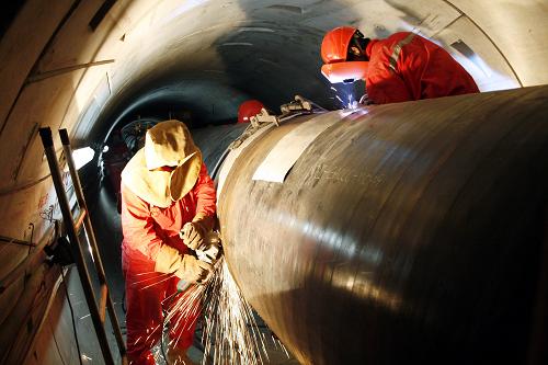 6月4日,工人在西氣東輸二線長江盾構(gòu)隧道內(nèi)打磨、焊接管道。 西氣東輸二線重點控制性工程長江盾構(gòu)隧道,于2009年11月16日在江西省瑞昌市碼頭鎮(zhèn)和湖北省武穴市之間全線貫通,隧道水平長度2590米。2010年5月20日,隧道內(nèi)的管線安裝工作啟動,在直徑3.08米的隧道內(nèi)鋪設(shè)直徑1.219米的管線,目前已鋪設(shè)500米,預(yù)計管線安裝工程將在8月完工。 新華社發(fā)(張勇 攝)