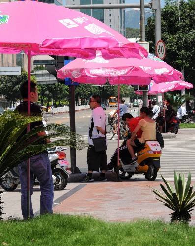 8月20日,在一個(gè)十字路口,等紅綠燈的行人在福州市交警部門(mén)撐起的遮陽(yáng)“愛(ài)心傘”下避暑。 新華社記者 來(lái)建強(qiáng) 攝