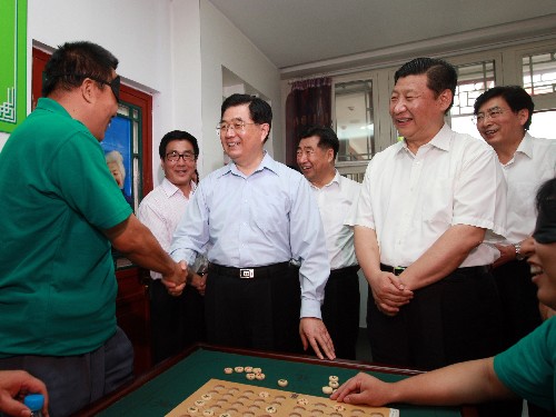 這是胡錦濤在北京市什剎海街道殘疾人溫馨家園的棋牌室同正在下棋的盲人親切交談。 新華社記者鞠鵬攝
