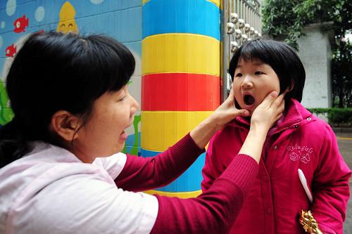 4月7日,廣州市白云區(qū)信孚澤德幼兒園的保健醫(yī)生(左)在對小朋友進(jìn)行晨檢。新華社記者 陳曄華 攝