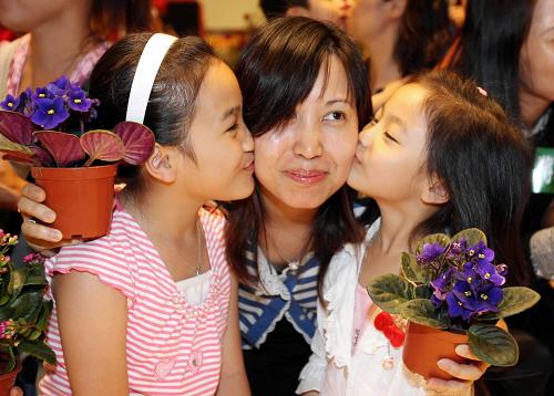5月10日,參加活動(dòng)的一位母親在接受兩個(gè)女兒的親吻。當(dāng)日,香港一大型商場(chǎng)舉辦“百人千花頌?zāi)笎?ài)”活動(dòng),迎接母親節(jié)。新華社記者 劉蓮芬 攝