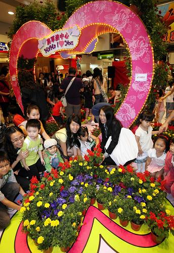 月10日,母親和孩子們一起堆砌“母親節(jié)愛(ài)心鮮花園”。當(dāng)日,香港一大型商場(chǎng)舉辦“百人千花頌?zāi)笎?ài)”活動(dòng),迎接母親節(jié)。新華社記者 劉蓮芬 攝