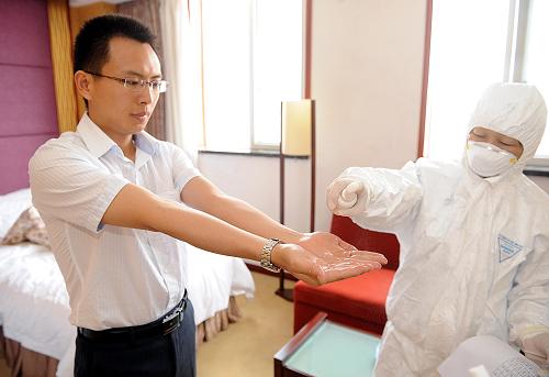5月16日,甲型H1N1流感集中觀察點(diǎn)——位于成都市龍泉驛區(qū)的某賓館內(nèi),工作人員正在給這位即將解除醫(yī)學(xué)觀察的趙先生做最后一次消毒。新華社記者 陳?ài)?攝