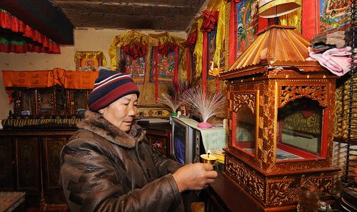 12月16日,拉薩城關(guān)區(qū)吉崩剛居委會的巴珠老阿媽在家里的佛龕前點酥油燈,她從2009年開始享受城鎮(zhèn)最低生活保障政策。新華社記者 格桑達(dá)瓦 攝