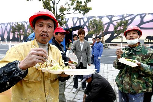 4月11日,來自河南駐馬店地區(qū)的李衛(wèi)中(左一)和工友們在世博園非洲館工地上吃飯,他笑呵呵地說:“時間緊、任務重,現在一日三餐都在工地吃了。”新華社記者 陳飛 攝