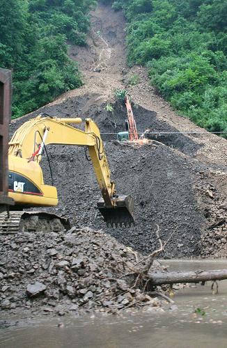 8月10日,在葦沙河鎮(zhèn)鴨綠江畔,施工人員在搶修被山體滑坡堵塞的道路。新華社記者 丁淵 攝
