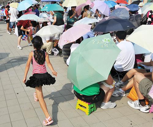 8月14日,游客在上海世博園五號門外等待開園。新華社記者 丁海濤 攝