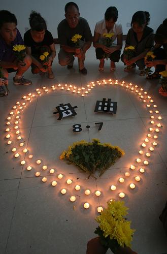 8月14日,山東濟南市南全福社區(qū)居民手捧菊花,點燃蠟燭,哀悼甘肅舟曲特大山洪泥石流遇難同胞。新華社發(fā)(呂傳泉 攝)