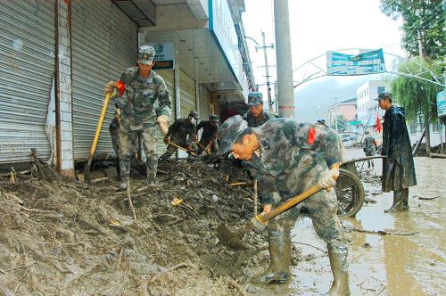 蘭州軍區(qū)鋼鐵紅軍師戰(zhàn)士在重災(zāi)區(qū)黃渚鎮(zhèn)街道清理淤泥(8月20日攝)。新華社記者 吳明軒 攝