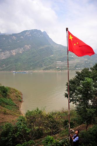 9月29日早晨,三峽移民顏道英在自家門前升起五星紅旗。湖北省秭歸縣西陵峽村四組移民顏道英家門前,總有一面鮮艷的五星紅旗迎風招展,顏道英一家是就地后靠移民,遷居后一家人的生活條件有了明顯改善。2004年開始,她老伴,20幾年的老村干部高秉鉗就天天帶著自己的兒孫在家門口舉行“升旗儀式”,表達對祖國的熱愛,直到2008年辭世。老伴去世后,顏道英接過老伴留下來的五星紅旗,在旭日東升的早晨,她做的第一件事就是升旗,既表達感恩,也寄托思念。新華社發(fā)(鄭家裕 攝)