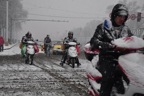 11月13日,黑龍江牡丹江市幾位市民冒著風(fēng)雪在街頭騎行。新華社發(fā)(張春祥 攝)