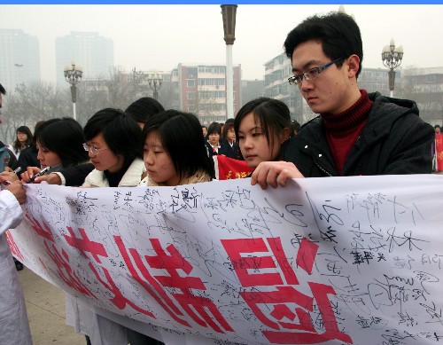 12月1日,在天津天塔公園參加“青春紅絲帶”行動(dòng)的志愿者在“遏制艾滋、履行承諾”的橫幅上簽名。