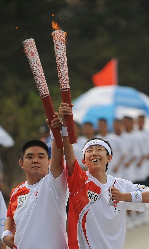 6月26日,奧運(yùn)火炬手高一凡(右)和郭偉平在傳遞過程中交接。當(dāng)日,北京奧運(yùn)圣火在山西大同傳遞。 新華社記者江宏景攝
