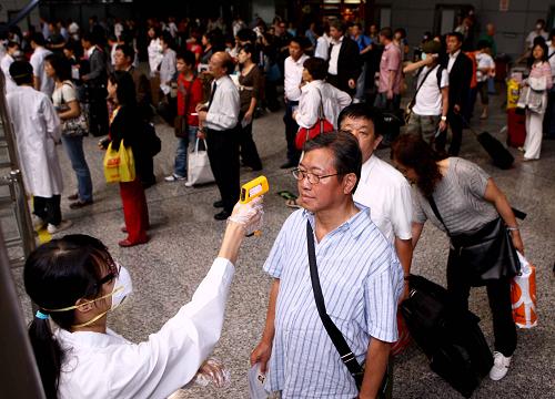 5月19日,來自廣東藥學(xué)院的一位志愿者在廣州天河口岸為入境旅客測(cè)量體溫。新華社記者 陳建力攝