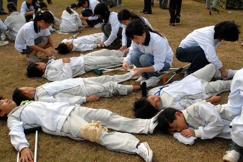12月8日,參加海口地震、火山應(yīng)急救援實(shí)戰(zhàn)演練的學(xué)生在“自救”和“互救”。