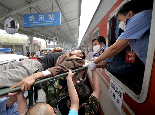 5月23日,在四川綿陽火車站,人們將傷員抬上專列。