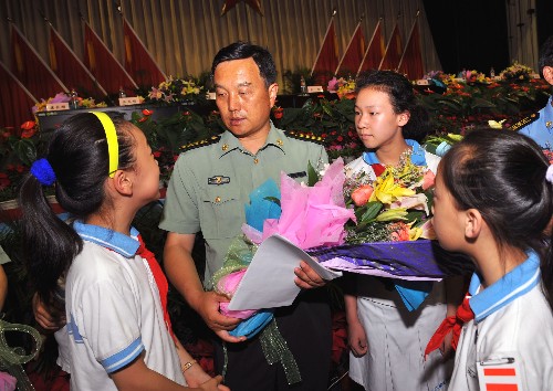 6月16日,成都軍區(qū)聯勤第38分部副部長康長順(左二)向參加報告會的成都泡桐樹小學學生介紹抗震救災時的情況。