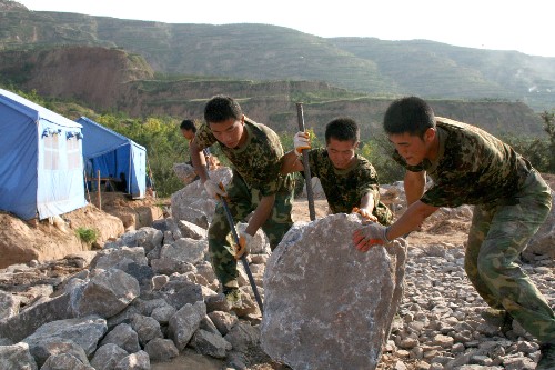 在甘肅省隴南市佛崖鄉(xiāng)賈店村,來自蘭州軍區(qū)某紅軍師金剛鉆團(tuán)的戰(zhàn)士在搬運(yùn)建房用的石塊(7月29日攝)。