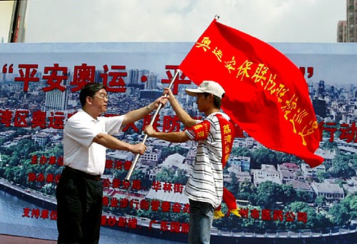 8月1日,廣州市荔灣區(qū)的有關(guān)負(fù)責(zé)人(左)將隊旗交給奧運(yùn)安保志愿者行動隊的代表。