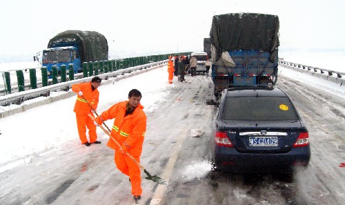 記者乘坐的北運瓜菜車--豫H60072汽車行駛在吉安到南昌的高速公路上,江西的救援人員在高速公路上撒鹽融冰(2月2日攝)。 新華社記者 周正平 攝