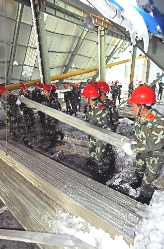2月3日,在浙江湖州市安吉縣一家被積雪損毀的廠房內(nèi),武警官兵在搶運(yùn)遭冰雪浸泡的鋁材。 新華社記者 譚進(jìn) 攝