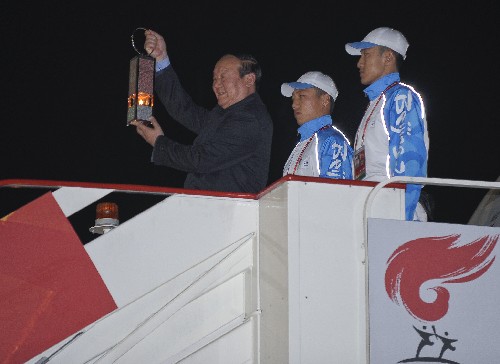 4月4日,北京奧組委執(zhí)行副主席蔣效愚(左)手持圣火火種燈走下飛機(jī)舷梯。 新華社記者 戚恒 攝