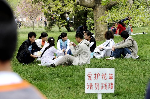 5月2日,一些游客圍坐在青島市中山公園內(nèi)的草地上。 新華社記者 李紫恒 攝