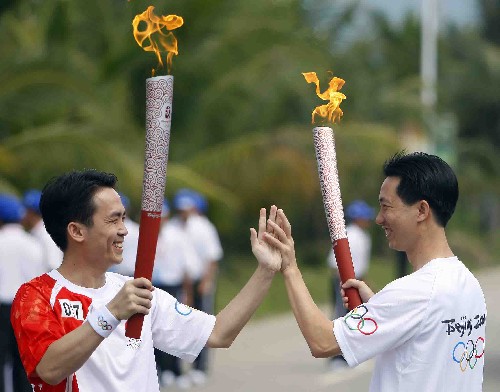 5月5日,火炬手賴學(xué)鵬與下一棒火炬手王昌江(左)交接后擊掌致意。當(dāng)日,北京奧運(yùn)會(huì)圣火傳遞活動(dòng)在海南萬寧市舉行。 新華社記者 邢廣利 攝