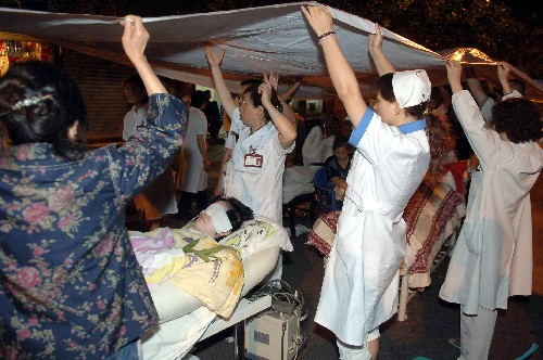 5月12日,汶川發(fā)生地震后,成都的醫(yī)護人員為“街頭病房”搭建臨時抗震棚。 5月12日,四川汶川地震波及成都,成都市民積極避險自救。目前,成都市區(qū)秩序正常。 新華社發(fā)(余坪 攝)