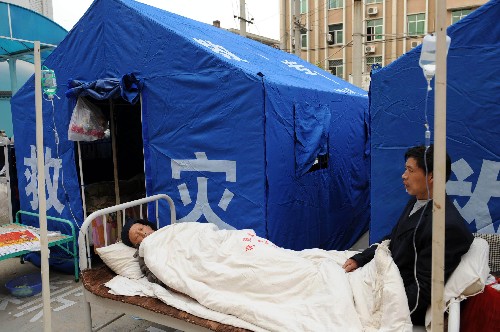 5月13日,陜西寧強縣受傷群眾在縣醫(yī)院的救災(zāi)帳篷旁輸液治療。 新華社記者 陶明 攝