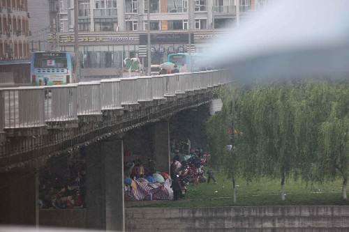 5月13日,四川綿陽市民在大橋下避雨。四川汶川地震波及綿陽市,導(dǎo)致該市受災(zāi)嚴(yán)重,市民紛紛在外搭建帳篷或在私家車內(nèi)住宿。 新華社記者 李剛 攝